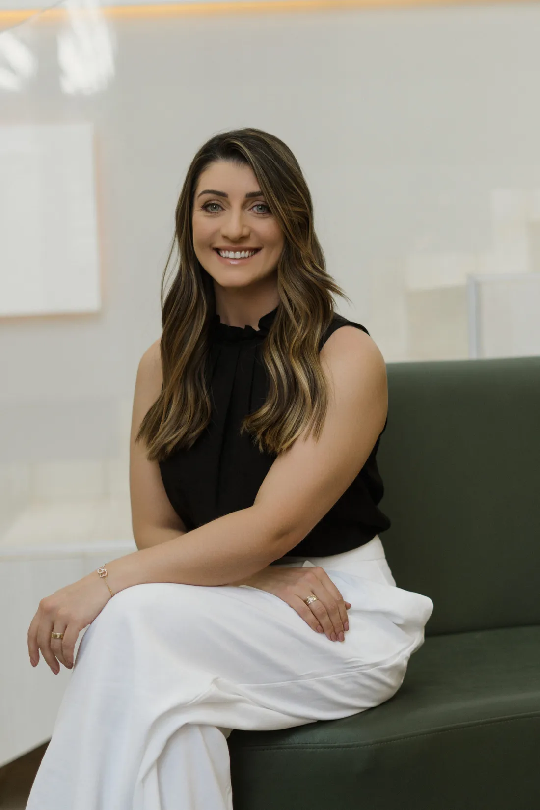 Ivana Bosa Colin sorrindo, sentada em um sofá verde